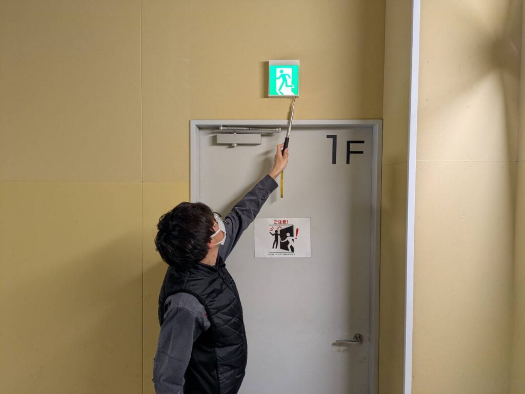 非常口誘導灯の点検を行っている作業員